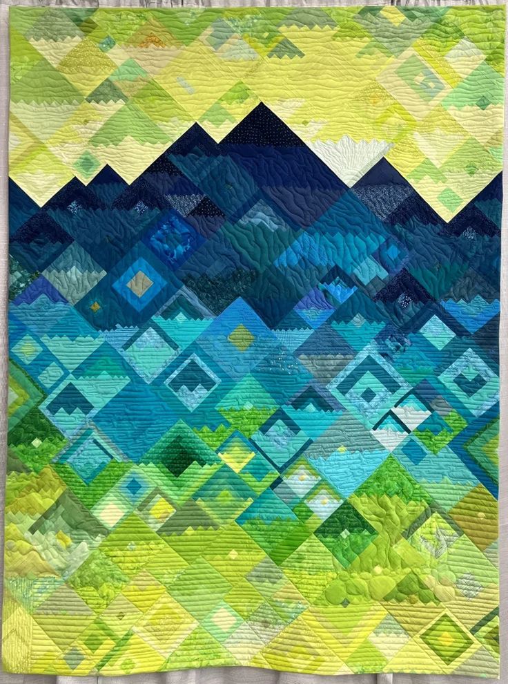 a quilted wall hanging with mountains in the background