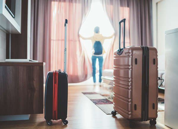 two pieces of luggage sitting on top of a hard wood floor next to a window