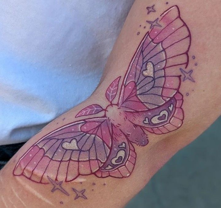 a woman's arm with a pink butterfly tattoo on the left side of her arm