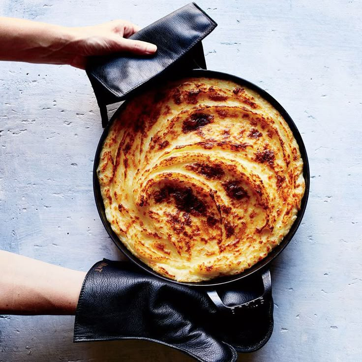 a person holding a skillet with some food in it