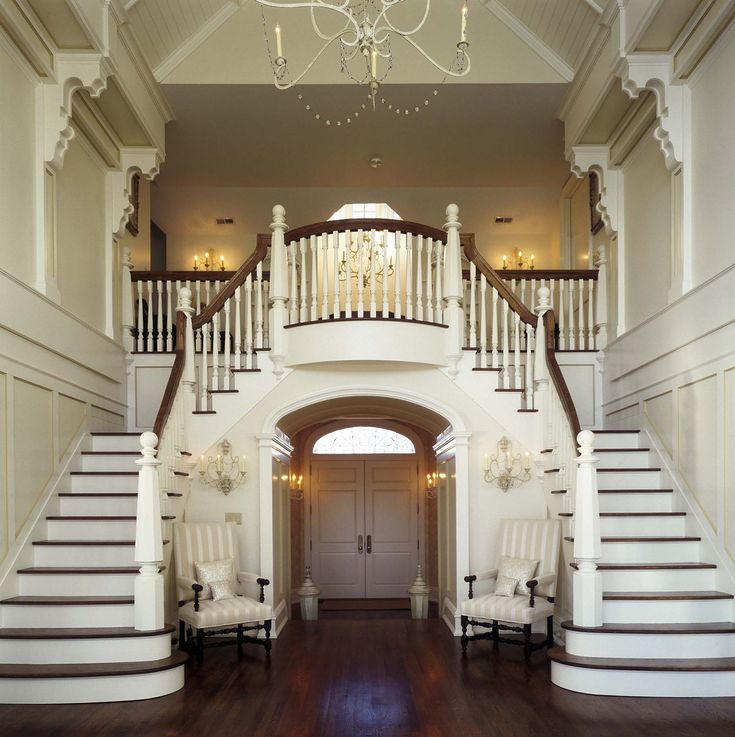 a large foyer with two white chairs under a chandelier