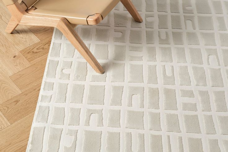 a chair sitting on top of a hard wood floor next to a white and gray rug