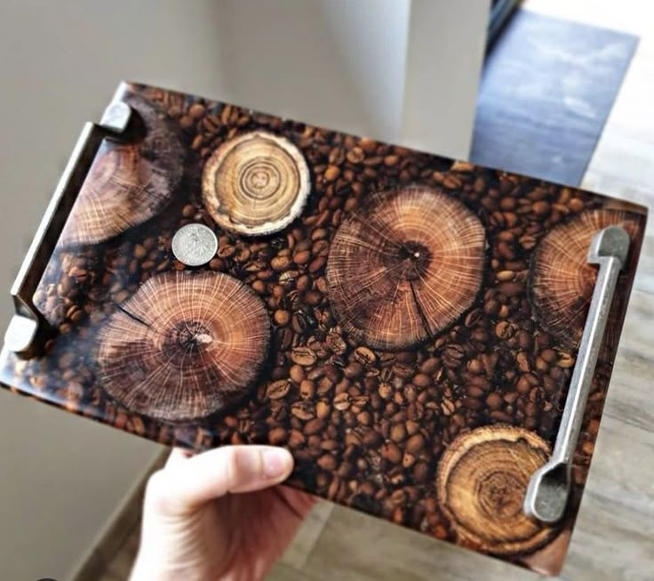 a person holding up a piece of wood that has been cut in half and is surrounded by coffee beans