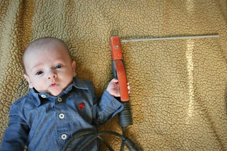 a baby laying on top of a bed with a hair dryer in it's hand