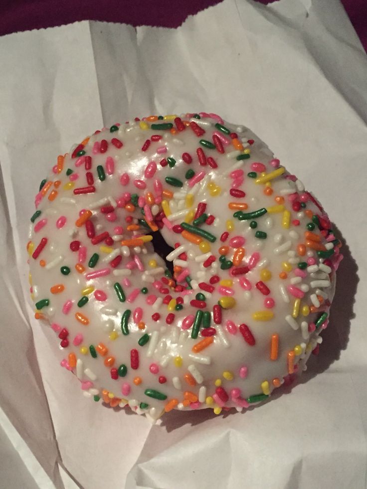 a white frosted donut with sprinkles sitting on top of tissue paper