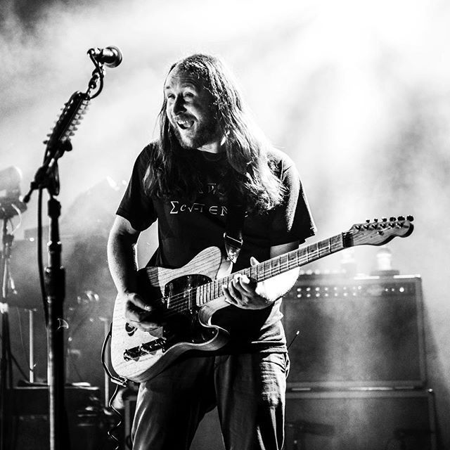 a man with long hair playing an electric guitar