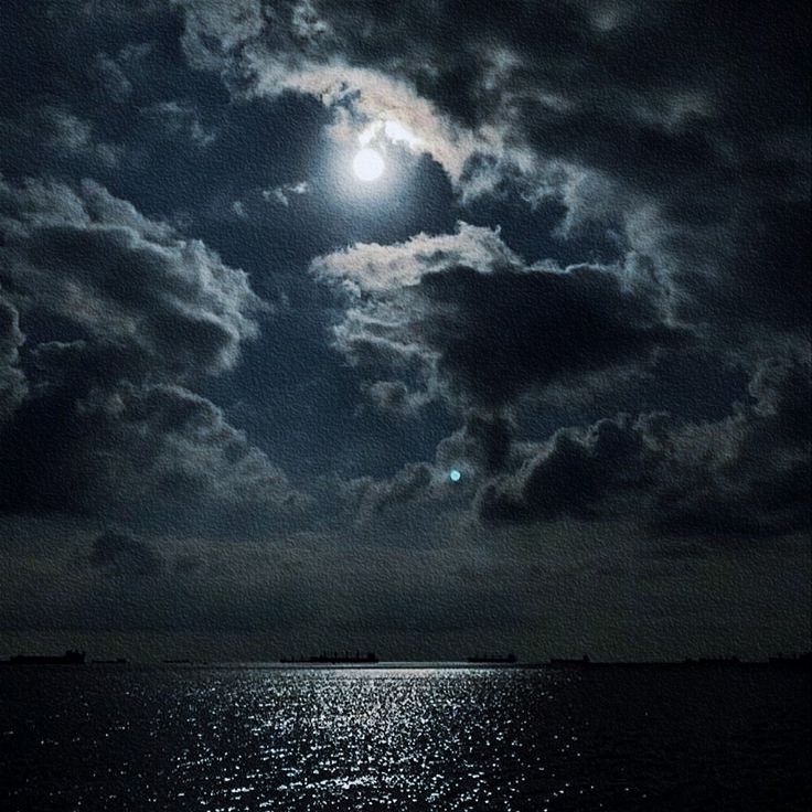 the moon shines brightly in the dark sky over the ocean as it reflects on the water