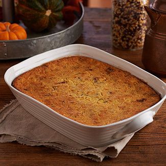 a casserole dish sitting on top of a wooden table next to pumpkins