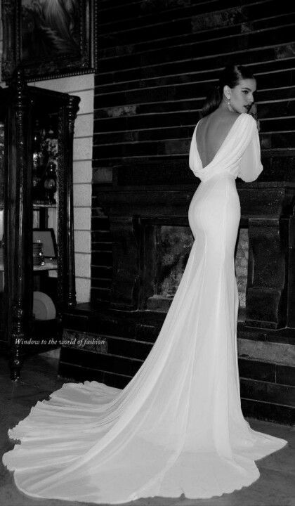 black and white photograph of a woman in a wedding dress looking at the back of her gown