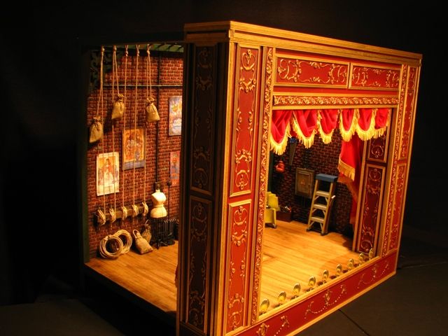 an elaborately decorated stage set with red curtains and wooden flooring, in the middle of a dark room