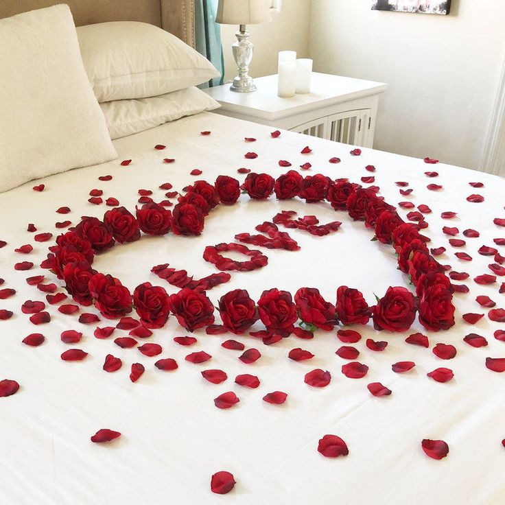 a bed with rose petals arranged in the shape of a heart