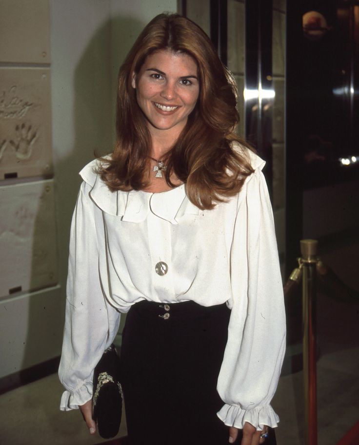 a woman in a white blouse and black skirt standing next to a refrigerator freezer