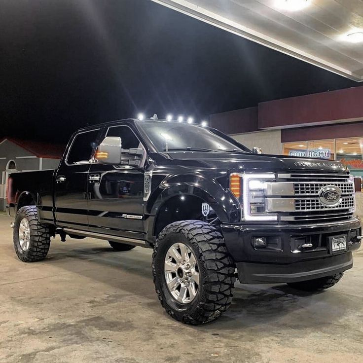 a black truck parked in a garage with lights on it's headlamps