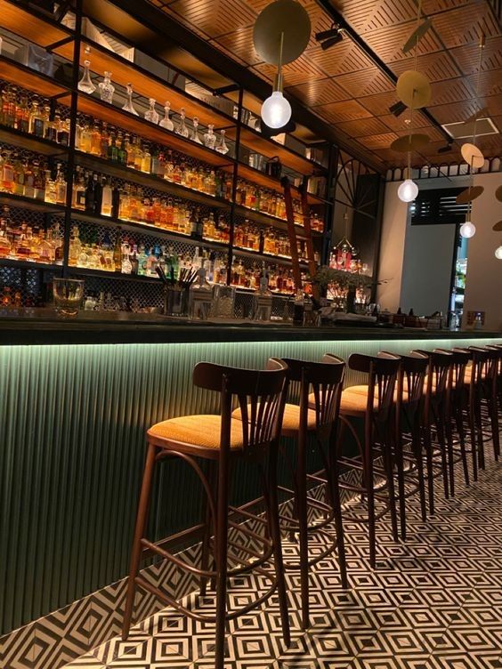 an empty bar with many chairs and shelves full of liquor bottles on the back wall