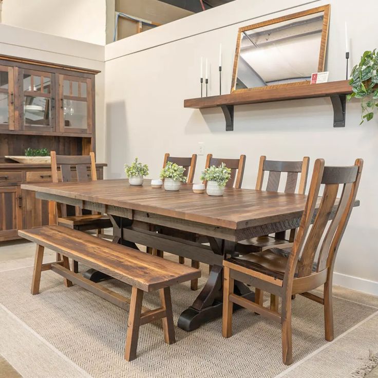 a dining room table and bench with potted plants