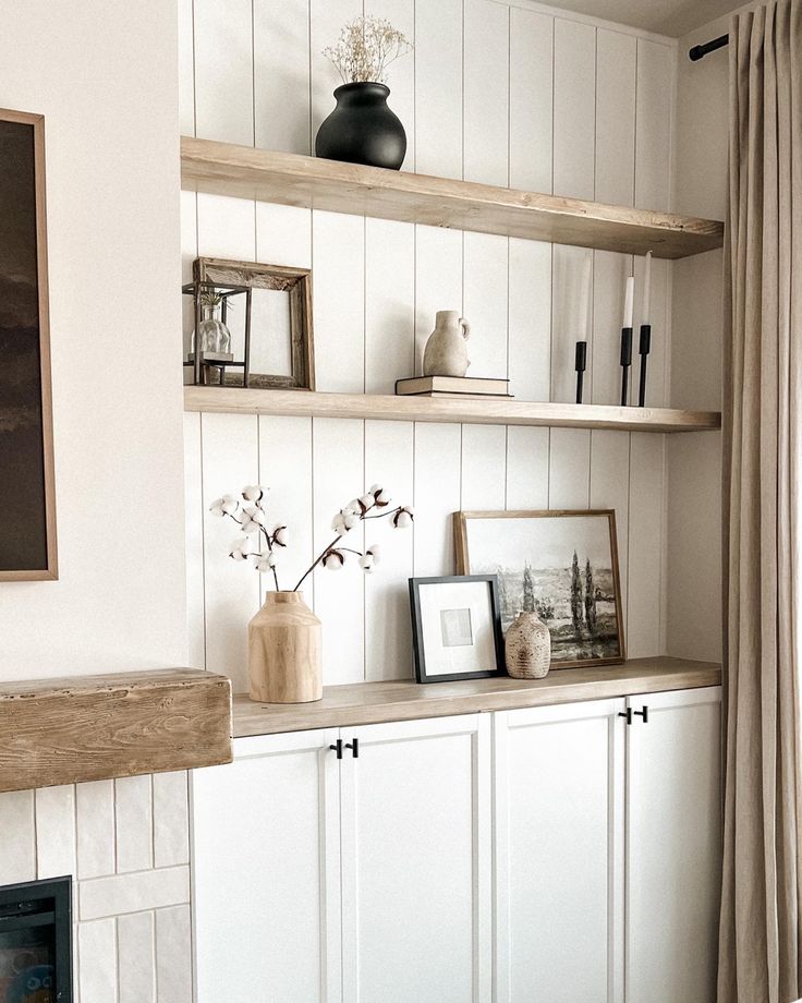 a living room filled with white furniture and shelves next to a fire place in front of a window