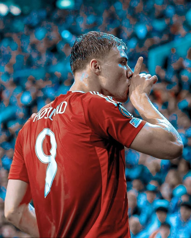 a man in red shirt holding his hand up to his mouth while standing next to a crowd