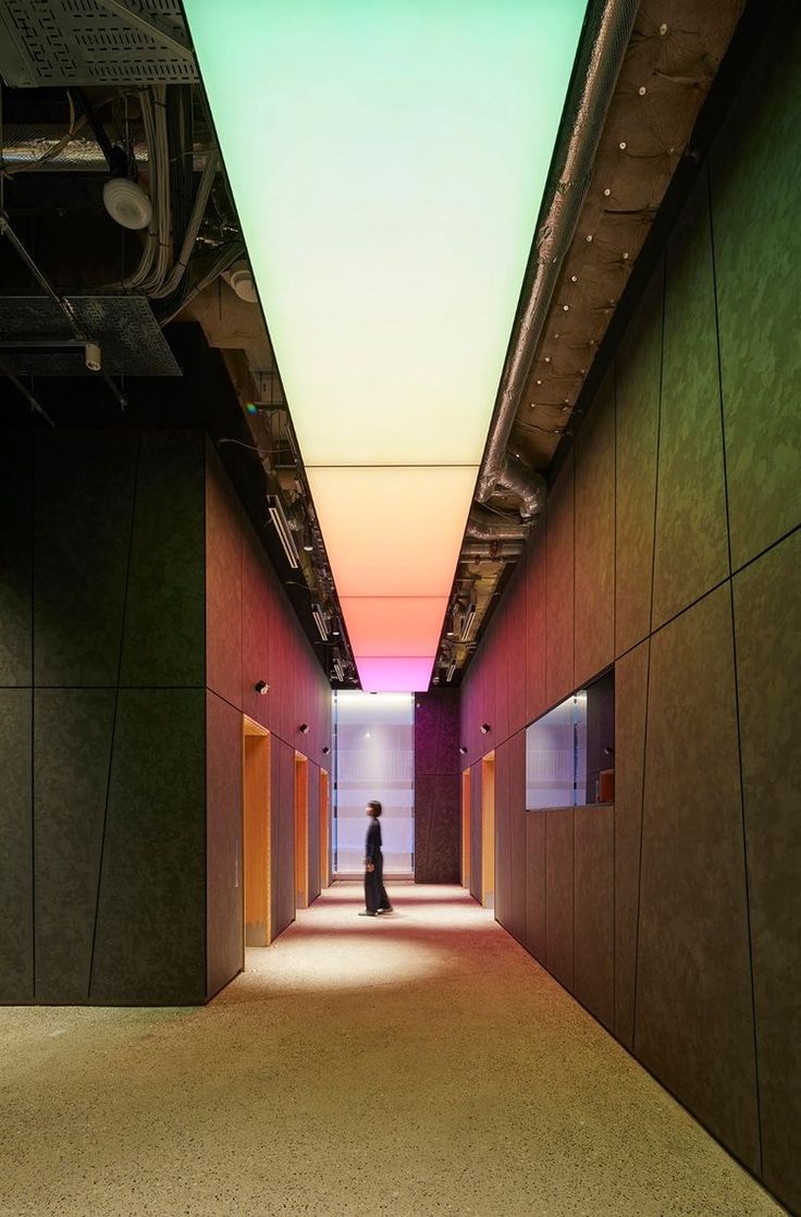 a person walking down a long hallway with lights on either side of the corridor and floor