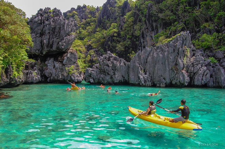 several people in kayaks paddling through clear blue water