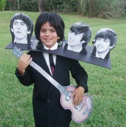 a boy in a suit and tie holding a guitar with pictures of himself on it