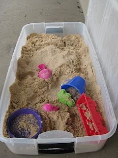 a plastic container filled with sand and toys