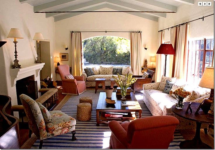 a living room filled with furniture and a fire place next to a window covered in curtains