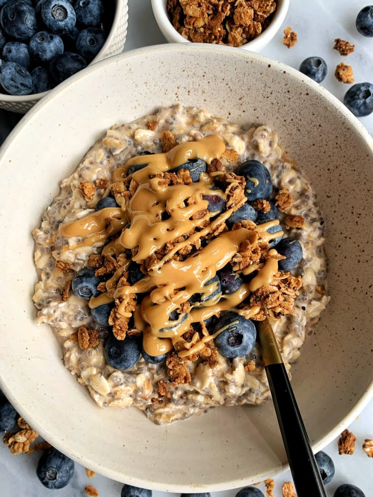 a bowl of oatmeal with blueberries and granola on the side