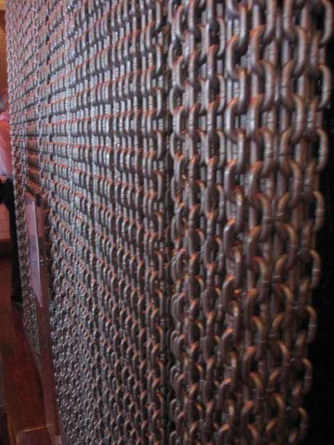 a wall made out of metal chains on top of a wooden floor