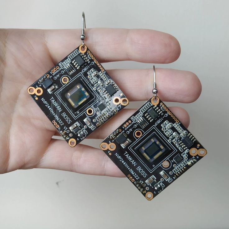 a hand holding two small square shaped electronics components