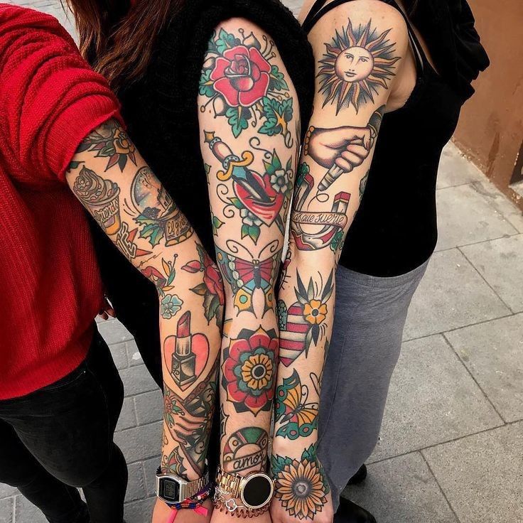 two women with tattoos on their arms are standing next to each other in front of a building