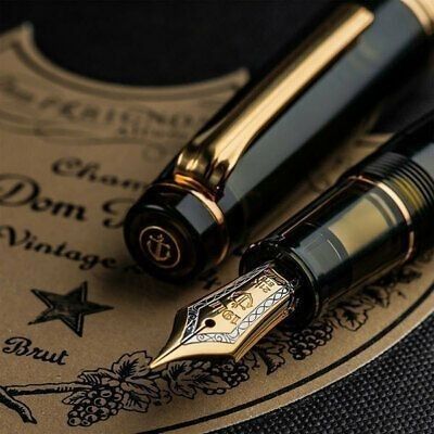 two fountain pens sitting on top of a paper with an ornate design and gold trim