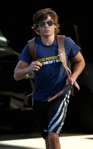 a young man is running down the street in shorts and a blue t - shirt