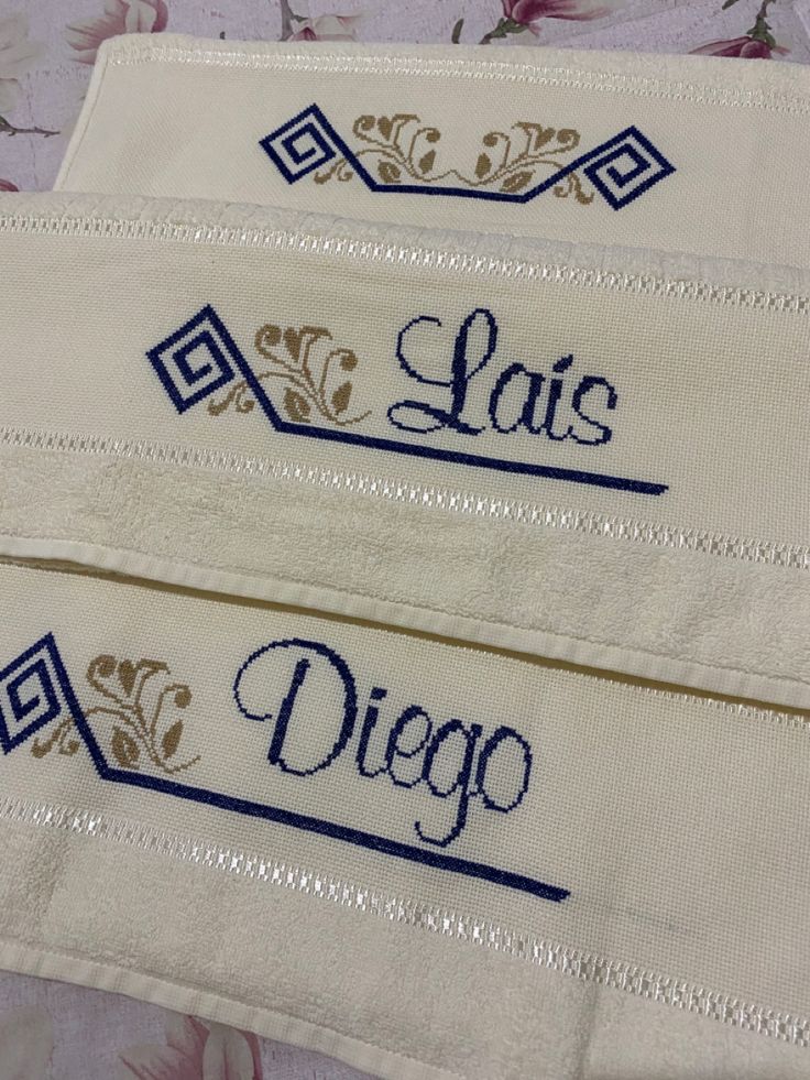 two embroidered name tags on white fabric with blue trimmings and floral patterning