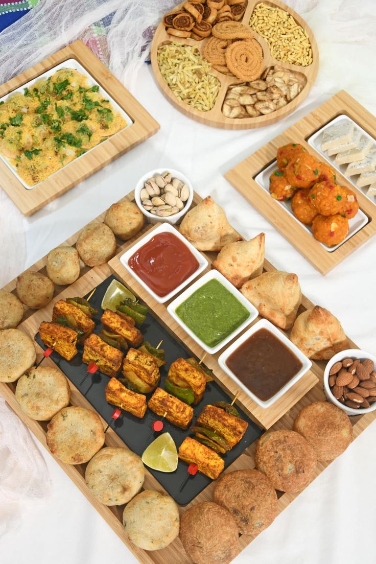 an assortment of food items displayed on wooden trays and serving platters with dipping sauces