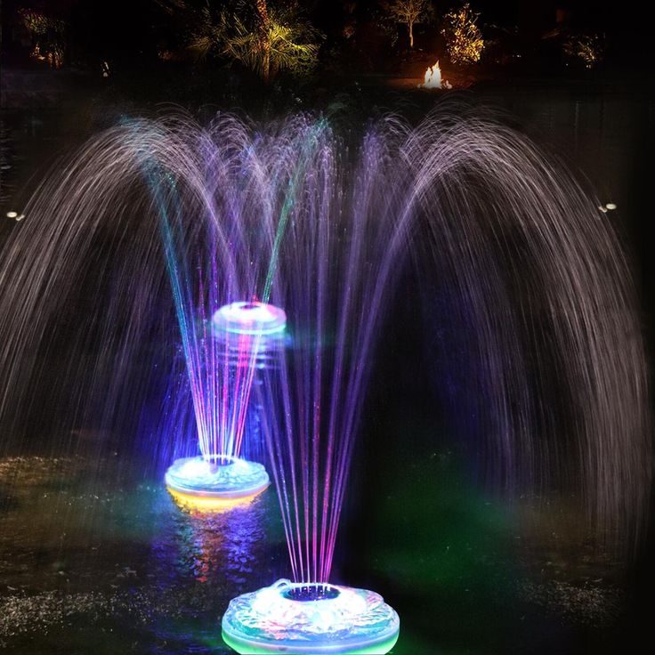 two water fountains in the middle of a pond with colorful lights on it's sides