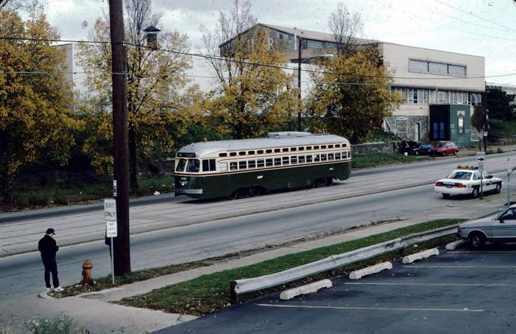 an old bus is parked on the side of the road next to a man standing in front of it