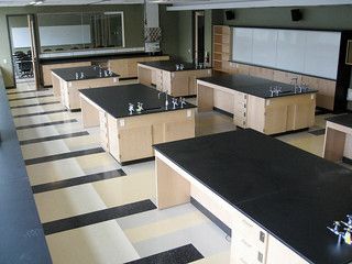 an empty classroom with black and white checkered flooring on the walls, desks and cabinets