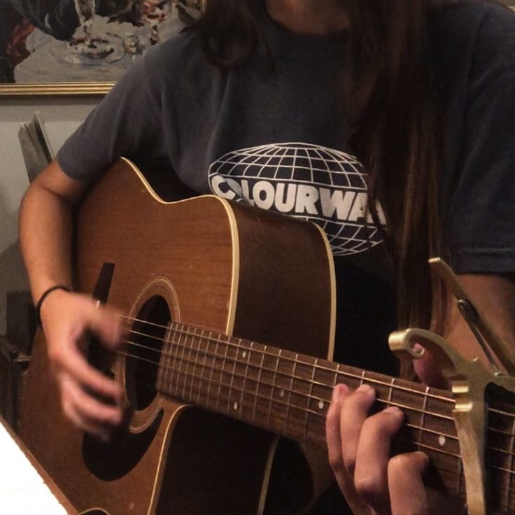 a girl playing an acoustic guitar in her living room