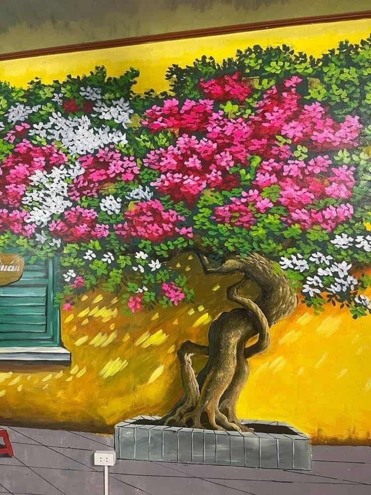 a painting on the side of a building with a tree and flowers painted on it