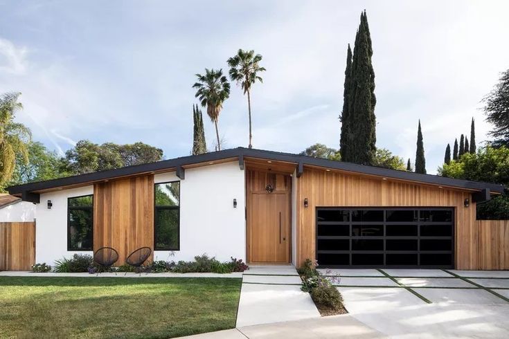 a house with palm trees in the background and two garages on either side of it