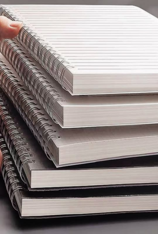 a stack of notebooks being held by a person's hand on a table