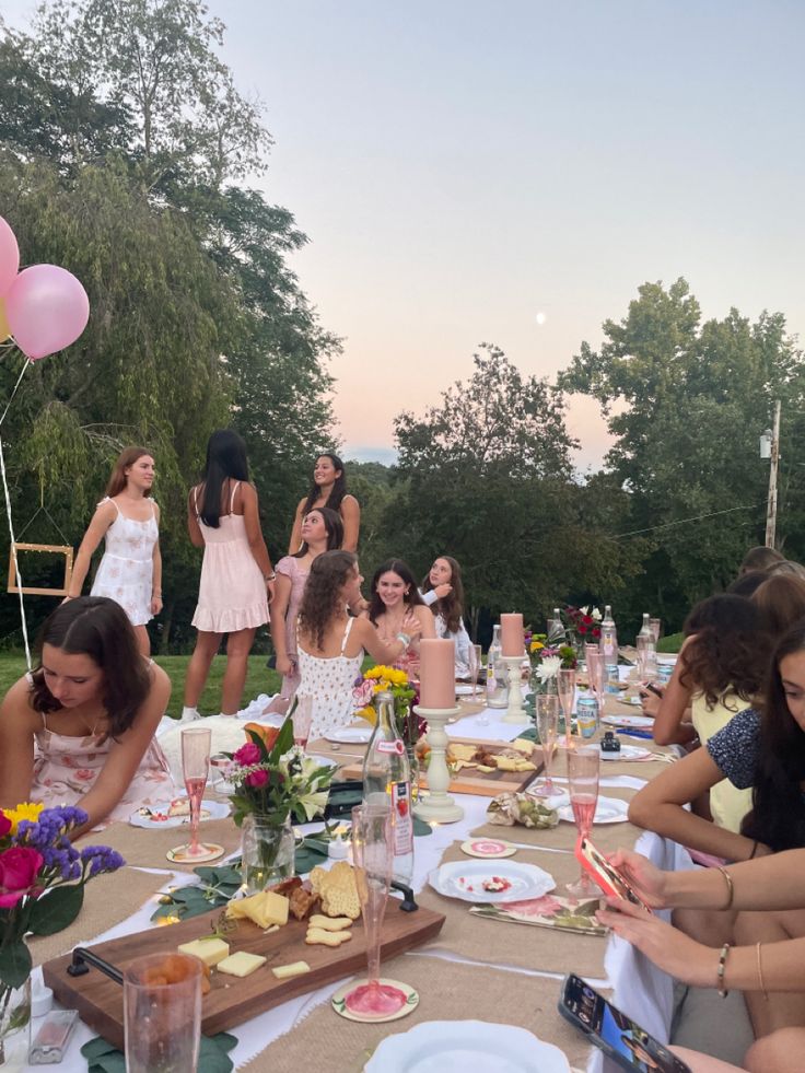 a group of women sitting around a table with plates and drinks on it, all dressed in pink