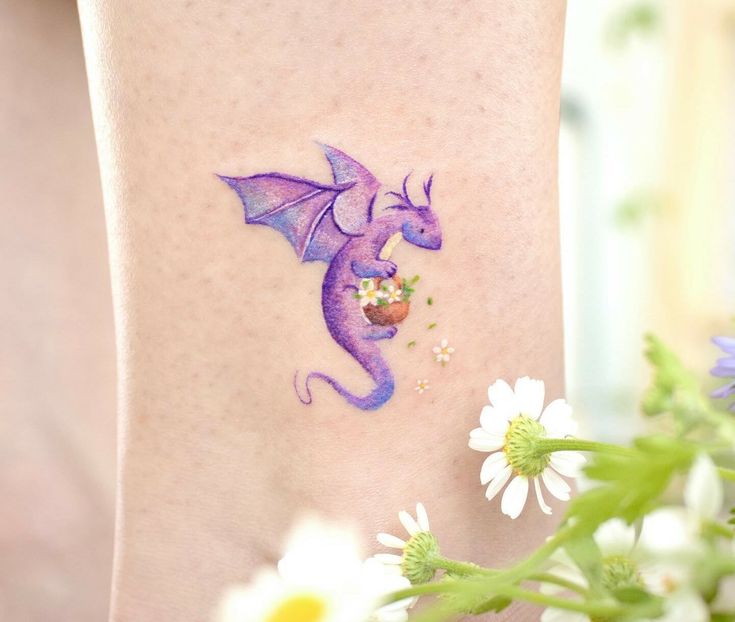 a small purple dragon with flowers on the side of its leg and it's wings spread out