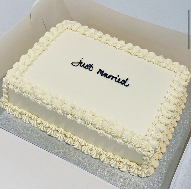 a square white cake with the words just married on it sitting in a cardboard box