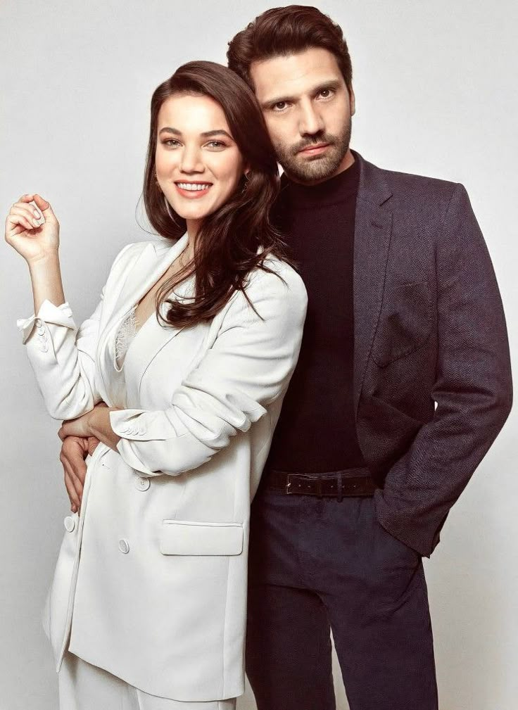 two people standing next to each other in front of a white background