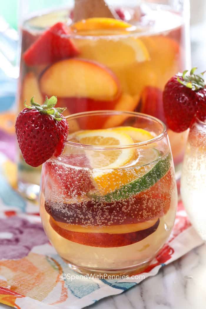 two glasses filled with liquid and fruit on top of a table next to each other