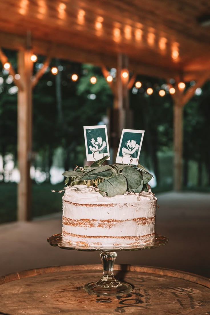 a wedding cake sitting on top of a wooden table in front of a gazebo