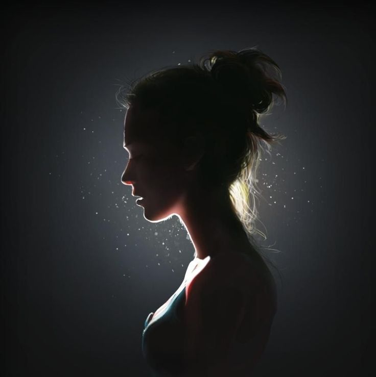 a woman's profile in the dark with light shining on her face and hair pulled back