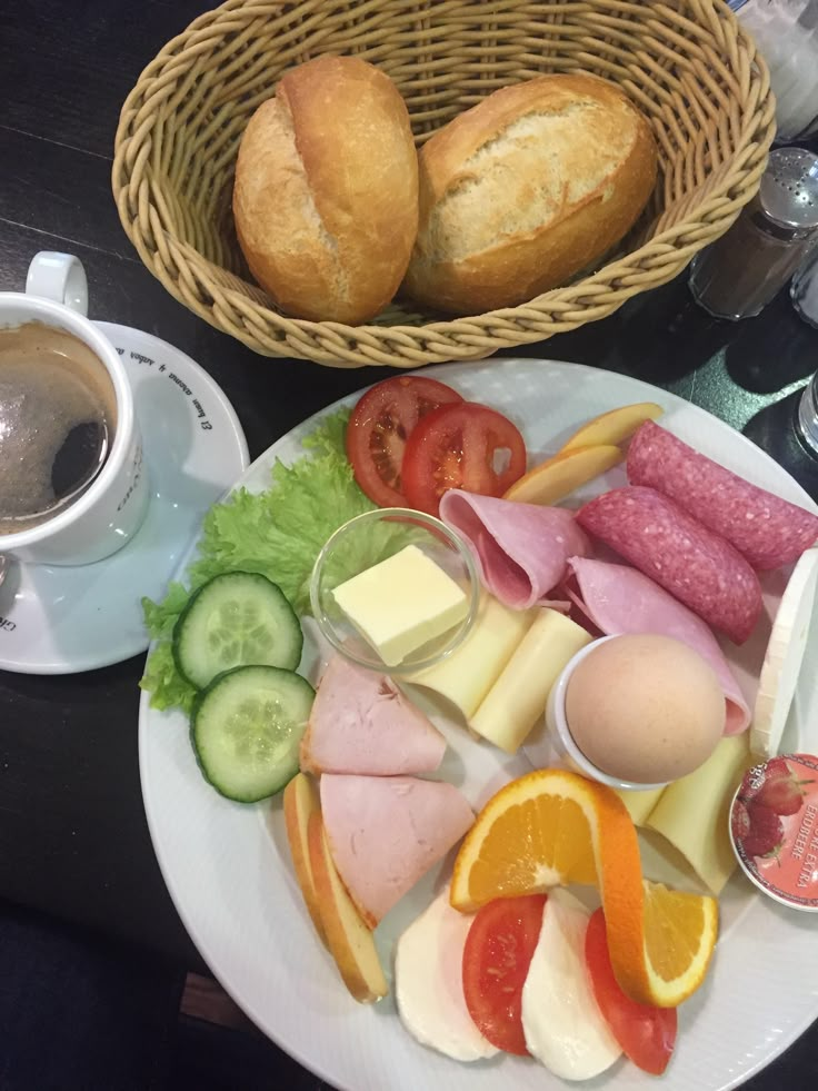 a white plate topped with lots of food next to a cup of coffee and bread