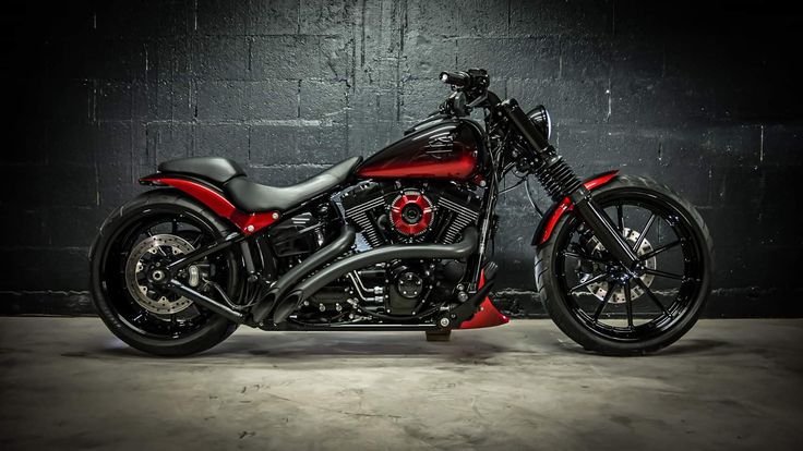 a red and black motorcycle parked in front of a brick wall